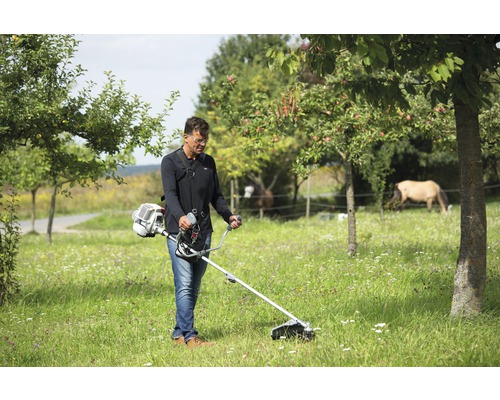 Mann benutzt Rasentrimmer in einem Garten