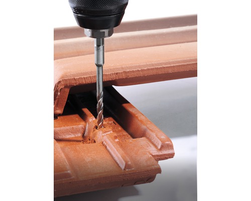 Bohrmaschine bohrt Loch in einen Dachziegel.