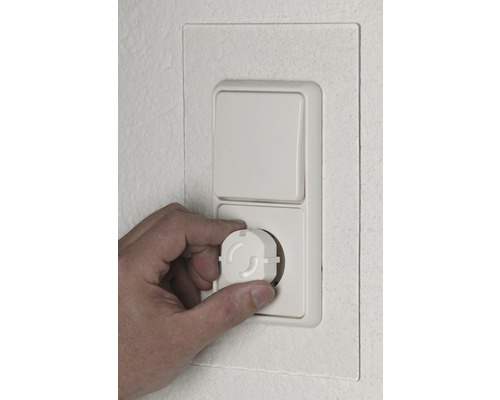 Hand setzt Kindersicherung in Steckdose ein