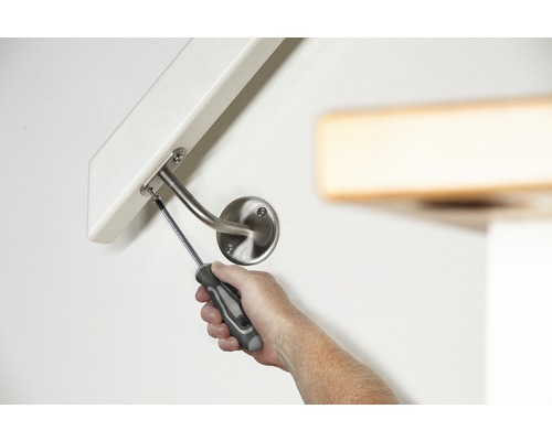 Eine Person montiert einen Handlauf mit einem Schraubenzieher an einer Wand.
