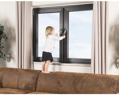 Kind steht auf einem Sofa und versucht, ein Fenster zu öffnen.