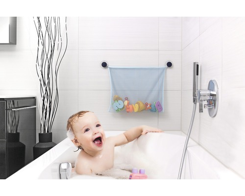 Ein Baby sitzt in der Badewanne mit Badespielzeug und einem Netz für Spielzeuge an der Wand.