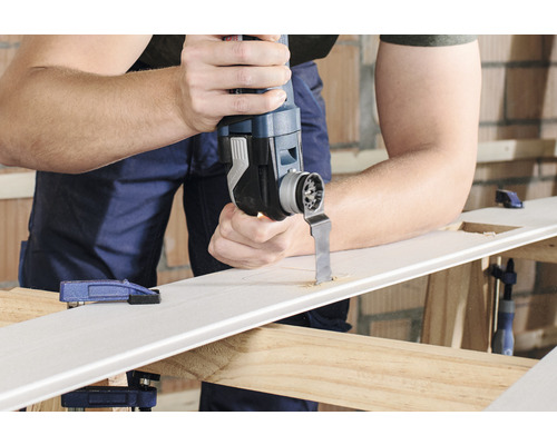 Mann schneidet mit einem Multifunktionswerkzeug ein Loch in ein Werkstück