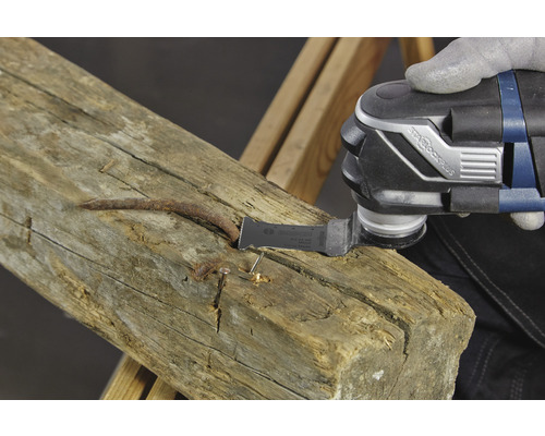 Multifunktionswerkzeug beim Bearbeiten eines Holzbalkens mit Nägeln.