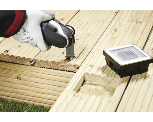 Oszillierendes Elektrowerkzeug beim Schneiden einer Holzterrasse für eine Bodeneinbauleuchte