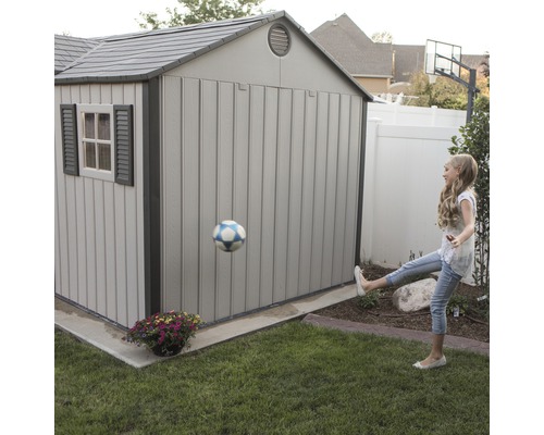 Gartenszene mit Gerätehaus und spielendem Kind mit Fußball