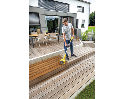 Mann behandelt Holzterrasse mit einem Holzölgerät