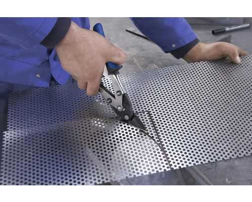 Eine Person schneidet Lochblech mit einer Blechschere.