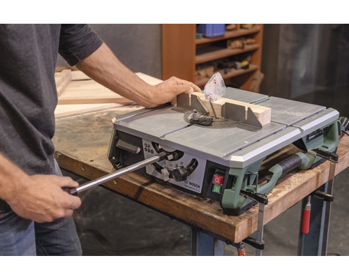 Person bedient Tischkreissäge mit Werkstück und Winkelanschlag. Bosch Logo.