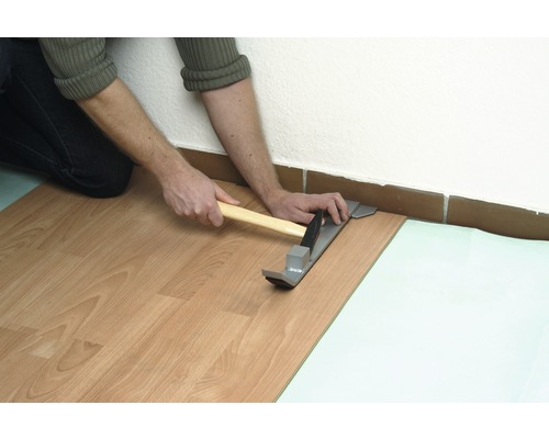 Verlegen von Laminat mit Zugeisen und Hammer