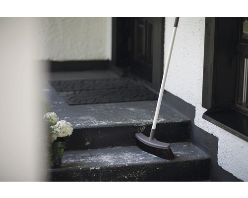 Besen auf einer Treppe vor einer Haustür