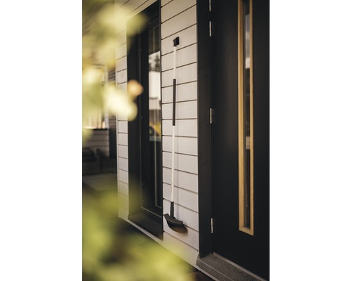 Kehrbesen an Hauswand neben Tür und Fenster