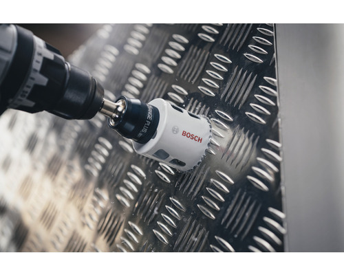 Bohrmaschine mit Bosch Lochsäge bohrt in eine Metallplatte