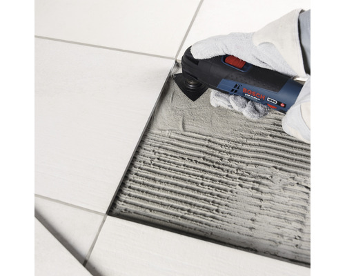 Multifunktionswerkzeug im Einsatz zum Entfernen von Fugenmasse zwischen Fliesen