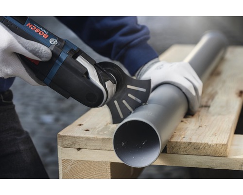 Oszillierendes Multifunktionswerkzeug schneidet ein Kunststoffrohr auf einer Holzpalette. Bosch Logo.