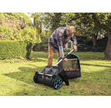 Ein Mann benutzt einen Kehrbesen im Garten, um Laub zu sammeln.