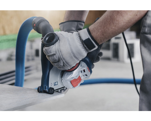 Eine Mauernutfräse in Aktion beim Schneiden von Stein, bedient von einer Person mit Handschuhen.