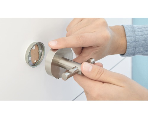 Eine Person montiert einen doppelten Kleiderhaken an der Wand.