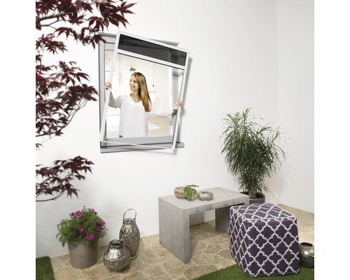 Frau montiert Insektenschutzgitter an einem Fenster im Außenbereich