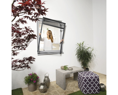 Frau befestigt Insektenschutzgitter am Fenster im Außenbereich