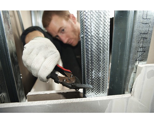 Mann schneidet Metallprofil mit Blechschere