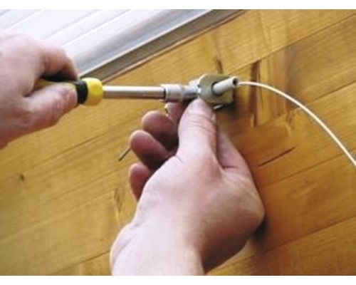 Eine Person montiert mit einem Schraubendreher eine Jalousie.