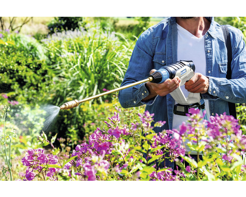 Eine Person benutzt ein Gartensprühgerät zum Gießen von Blumen.
