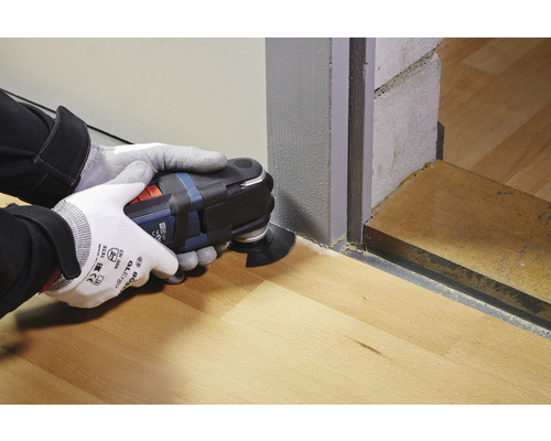 Eine Person arbeitet mit einem Multifunktionswerkzeug auf einem Holzboden.