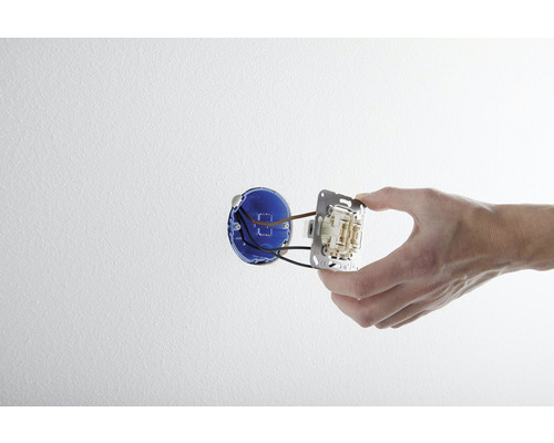 Hand montiert einen Lichtschalter in einer Wanddose.