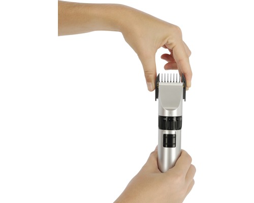 Eine Hand befestigt einen Aufsatz an einem Haarschneider.
