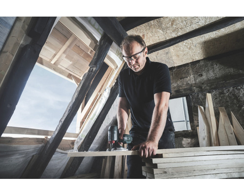 Handwerker arbeitet mit einer Oberfräse in einem Dachgeschoss.