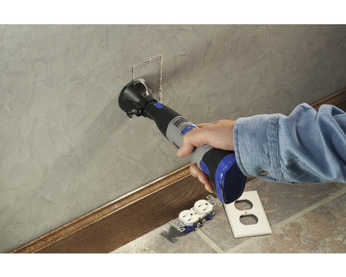 Eine Person verwendet ein Multifunktionswerkzeug zum Schneiden einer Öffnung in eine Wand für eine Steckdose.