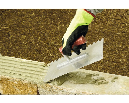 Handwerker verwendet eine Traufel zum Verlegen von Steinen.