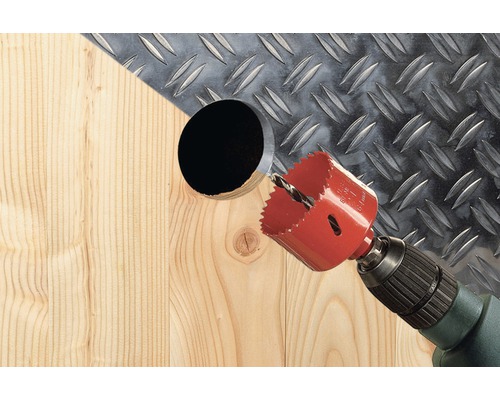 Lochsäge bohrt ein Loch in Holz vor einer Metallplatte