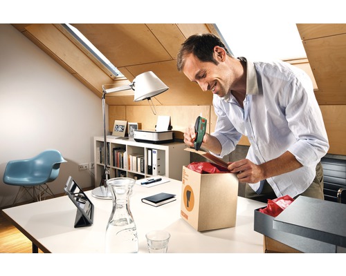 Mann verschließt einen Karton mit einem Akku-Tacker in einem Büro.