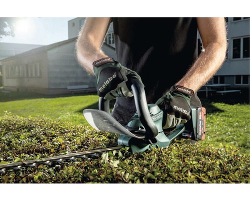 Eine Person schneidet mit einer Metabo Akku-Heckenschere eine Hecke