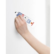 Eine Hand verwendet Alpina SOS Loch und Rissfüller Tube zum Ausbessern einer Wand