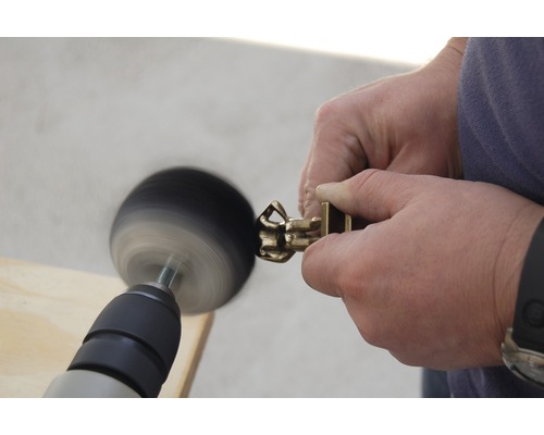 Eine Person poliert ein Messingprodukt mit einer rotierenden Bürste.