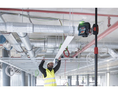 Ein Arbeiter mit Schutzhelm und Warnweste montiert eine Decke mit einem Laser Nivelliergerät von Bosch.