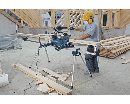 Mann arbeitet mit einer Bosch Kapp- und Gehrungssäge mit Werkbank auf einer Baustelle