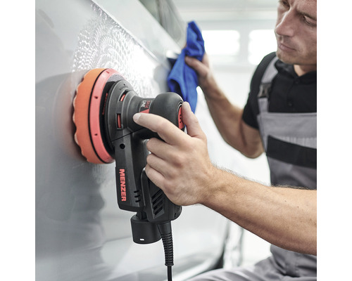 Mann poliert Auto mit Poliermaschine und Mikrofasertuch.