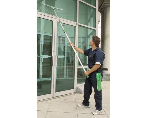 Mann reinigt Fenster mit Fensterwischer und Teleskopstiel