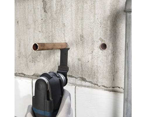 Multifunktionswerkzeug beim Kürzen eines Kupferrohrs an einer Wand