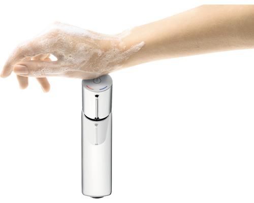 Eine Hand mit Seife berührt eine Armatur zur Wasserentnahme.