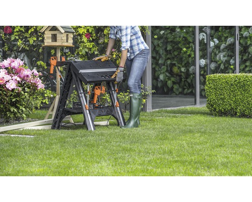 Frau arbeitet an einer klappbaren Werkbank im Garten.