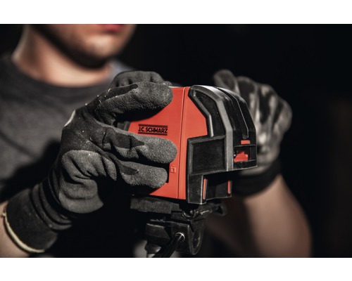 J.C. Schwarz Logo auf einem Kreuzlinienlaser, gehalten von einer Person mit Handschuhen