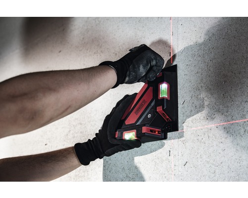 Eine Person befestigt einen Kreuzlinienlaser an einer Wand.