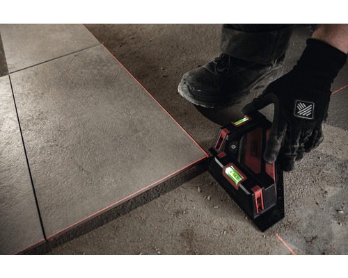 Person verlegt Fliesen mit einem Linienlaser zur Ausrichtung.