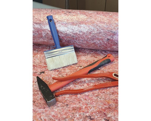 Werkzeuge und Dämmstoffrolle liegen auf dem Boden.