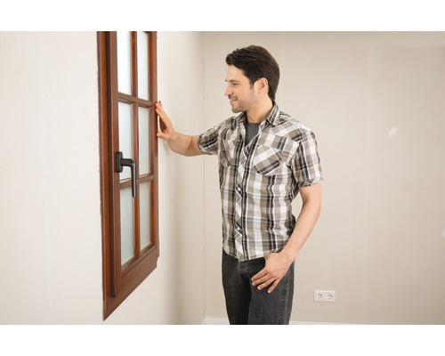 Mann betrachtet ein Holzfenster mit Griff